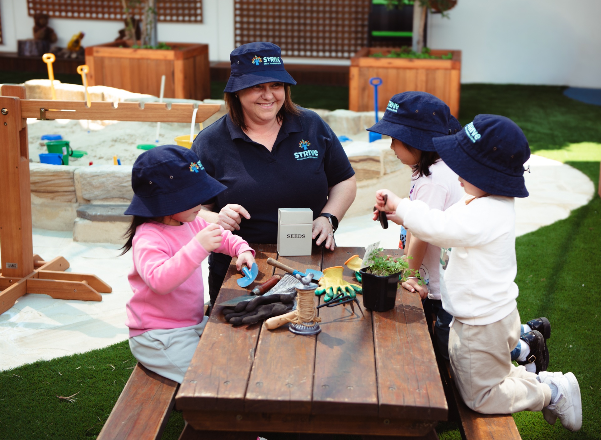 Educator and children gardening at picnic table